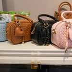 Four handbags in different colors on a display table.