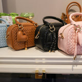 Four handbags in different colors on a display table.