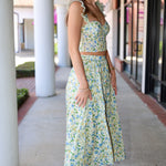 Woman in a floral skirt set standing on a sidewalk with columns in the background