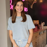 Woman in light blue outfit standing in front of a neon sign indoors
