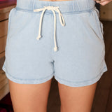 Light blue denim shorts with a drawstring worn by a person.
