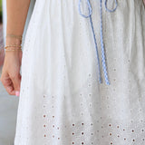 White eyelet skirt with blue drawstring and a blurred background