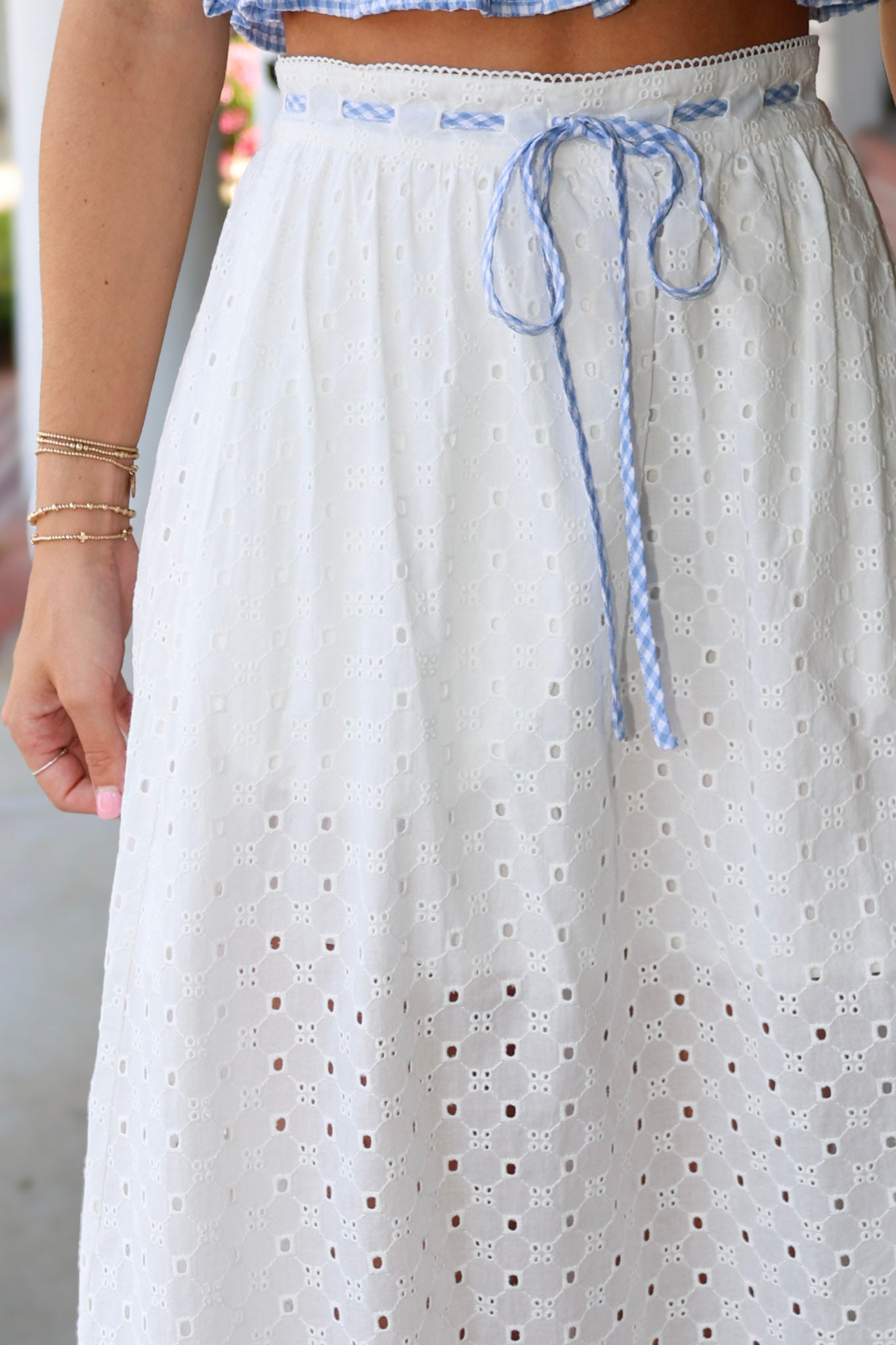 White eyelet skirt with blue drawstring and a blurred background