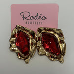 Gold and red earrings on a pink card with 'Rodeo Boutique' branding.