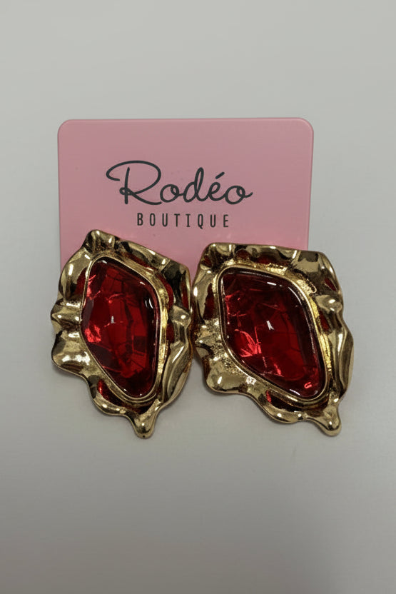 Gold and red earrings on a pink card with 'Rodeo Boutique' branding.